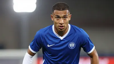A photorealistic image of an anonymous 22-year-old AJ Auxerre midfielder, dressed in a blue and white jersey, with a...