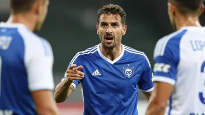 A mid-30s Auxerre player in a blue and white kit, waist-up, shouting instructions to teammates