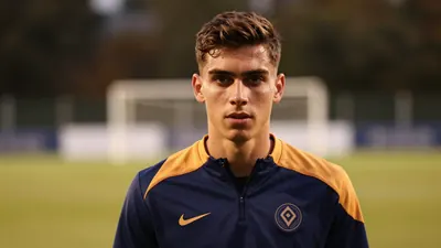 A young, athletic Auxerre left-back, 20s, with determined expression, wears a plain blue and amber training top, against...