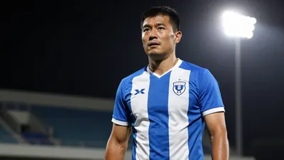 A 30-year-old male coach with a strong build, wearing a blue and white striped jersey, standing in a stadium with a...