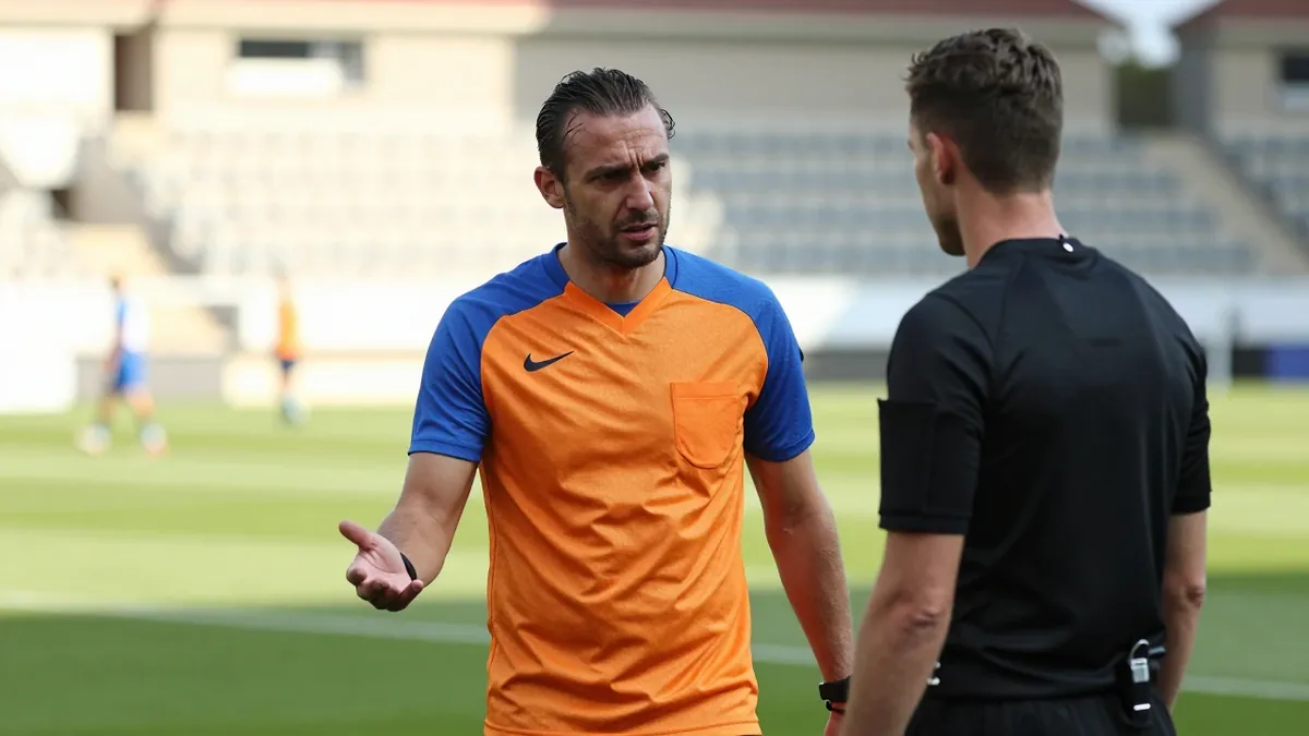 A 35-year-old, 5'10" athletic male in a plain blue and amber polyester training top, his dark hair slicked back, looks...