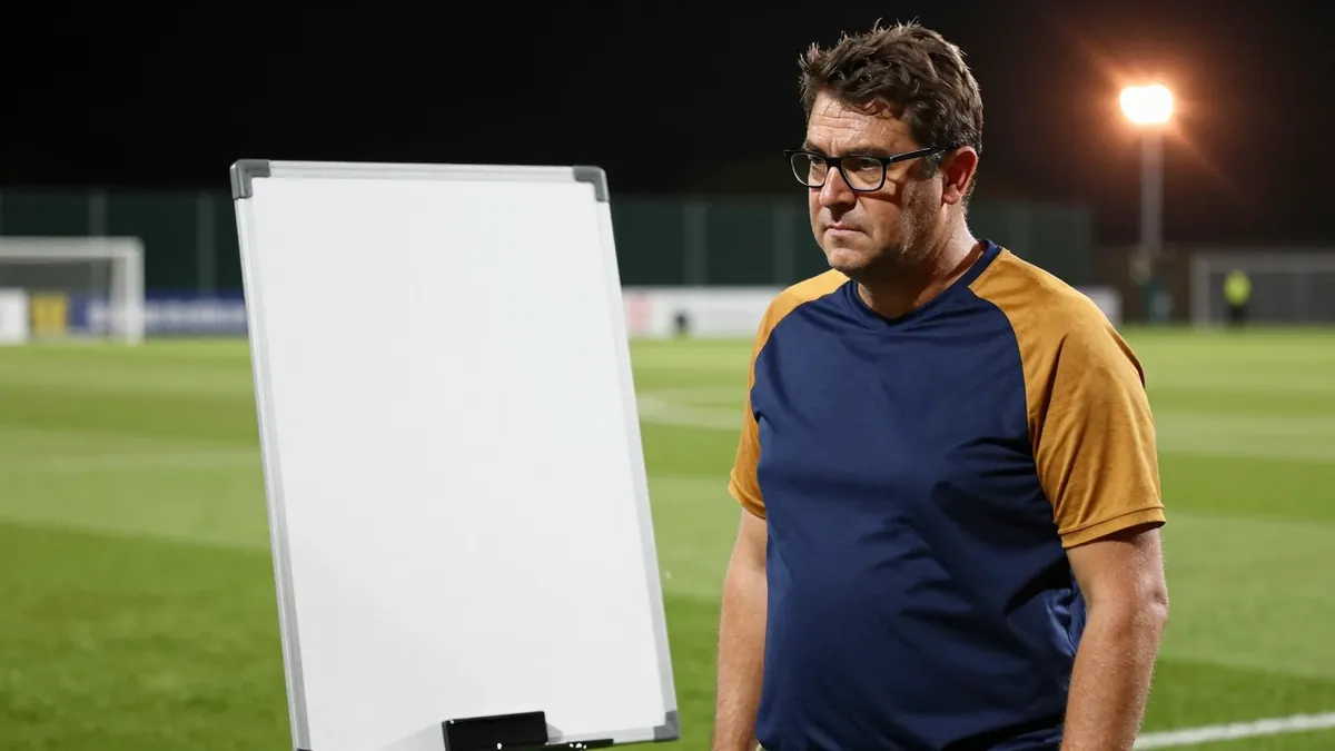 A 35-year-old, stocky, bespectacled assistant coach with a rugged complexion, wearing a plain blue and amber polyester...