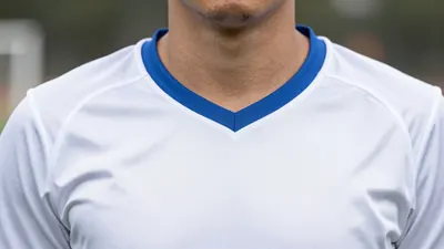 A photorealistic image of an anonymous AJA player in a white shirt with blue facings, with a clean solid block of white...