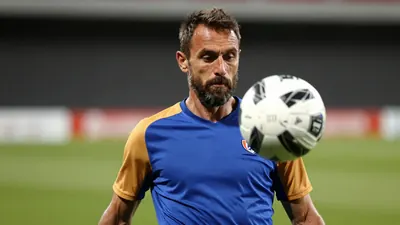A 50-year-old, 5'10" male Auxerre player with a rugged build, sporting a short, dark brown beard, focuses intensely on...